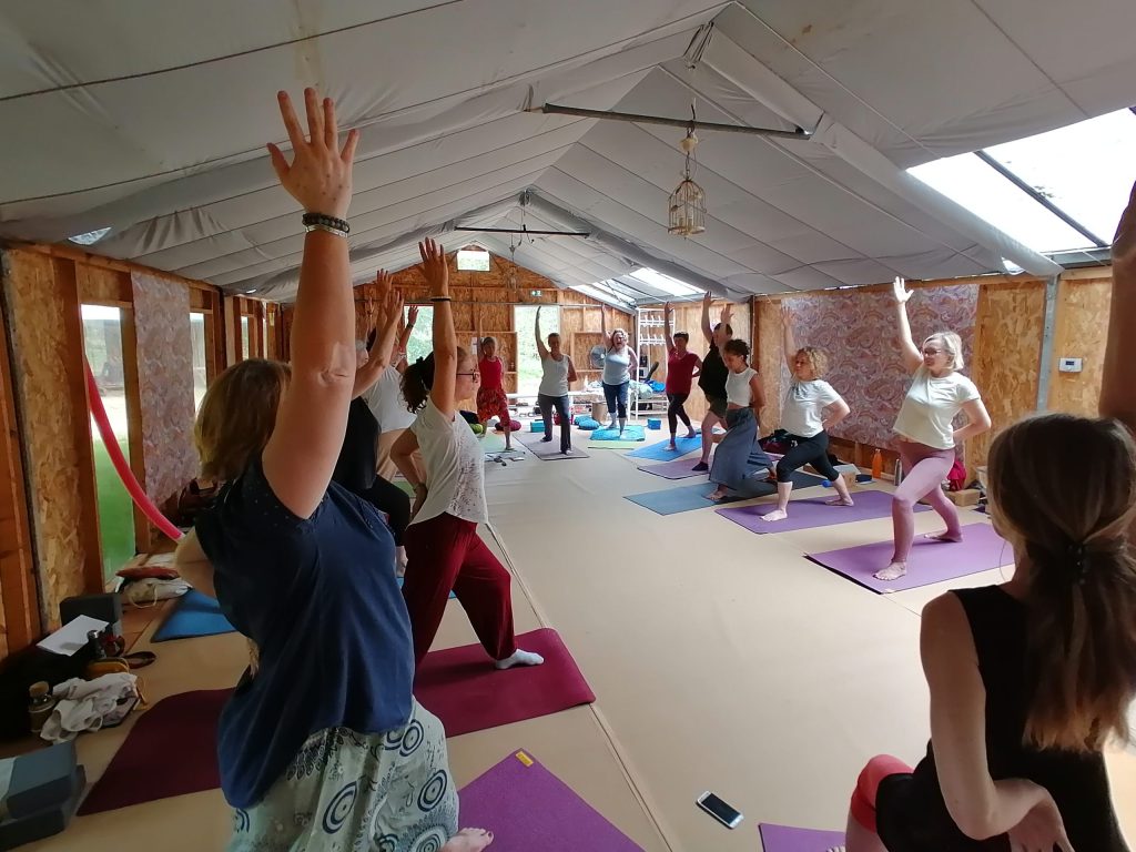 Séance de yoga en groupe dans une salle lumineuse, accompagnée par Stéphane Anselmino