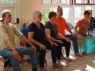 Groupe de seniors en posture debout avec appui sur une chaise